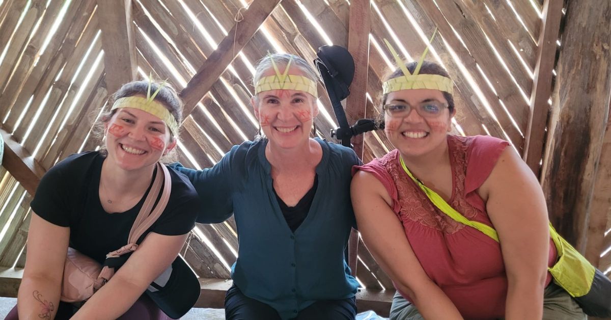Three students smiling with their faces painted and wearing decorative headbands.