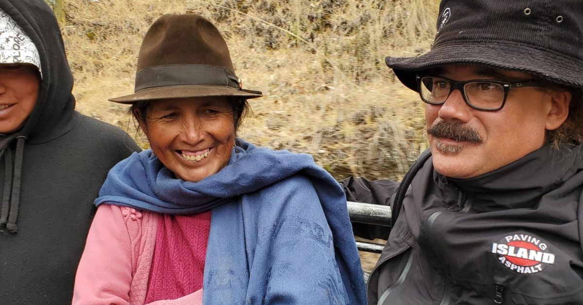 Three smiling people sitting in the back of a pick up truck.