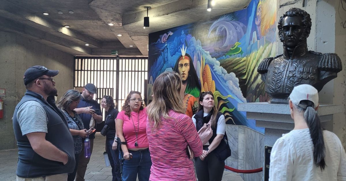 Students looking at a statue on display in a concrete building.