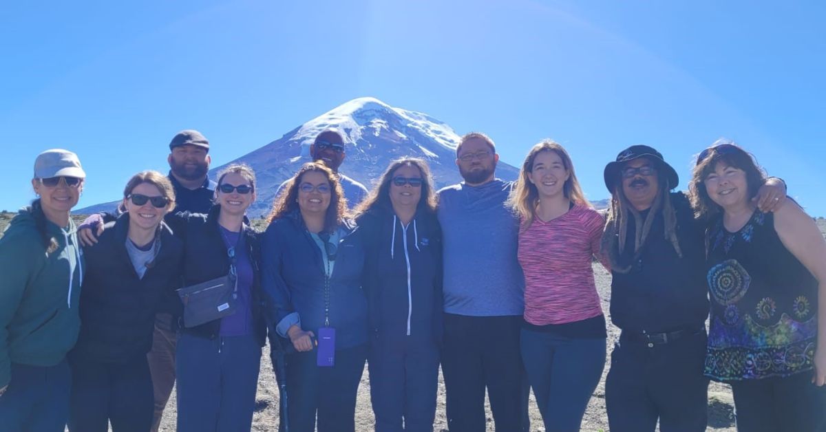 A group of people standing in front of ice-topped mountain.