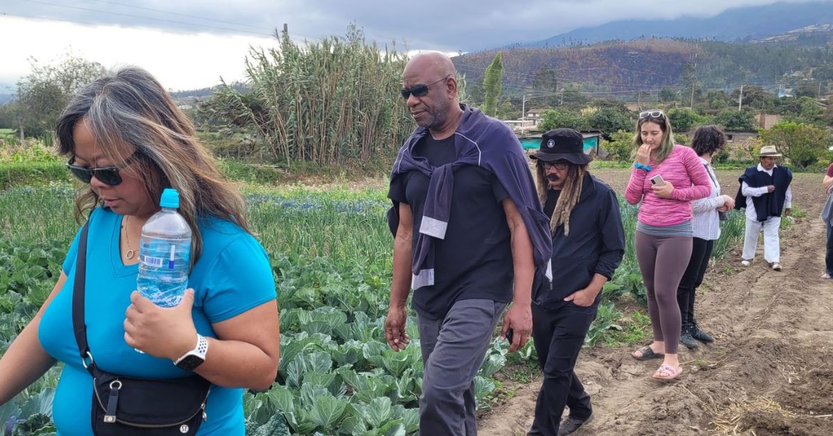 Students walking along a dirt path beside a farm field.