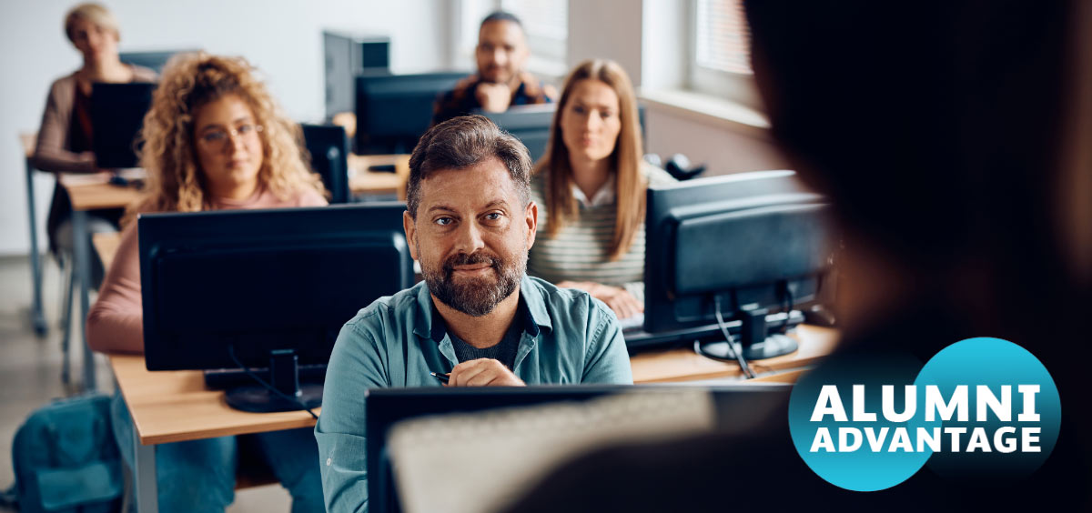 A classroom of Royal Roads alumni look onward toward their instructor while sitting in front of their monitors.