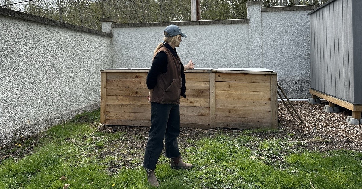 Woman looking at a large wooden compost box.