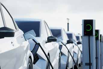 A row of electric vehicles plugged into charging stations