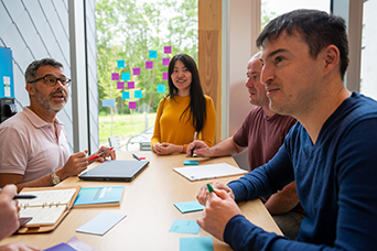 A group of RRU employees sit around a table in discussion. This image links to information for RRU employees.