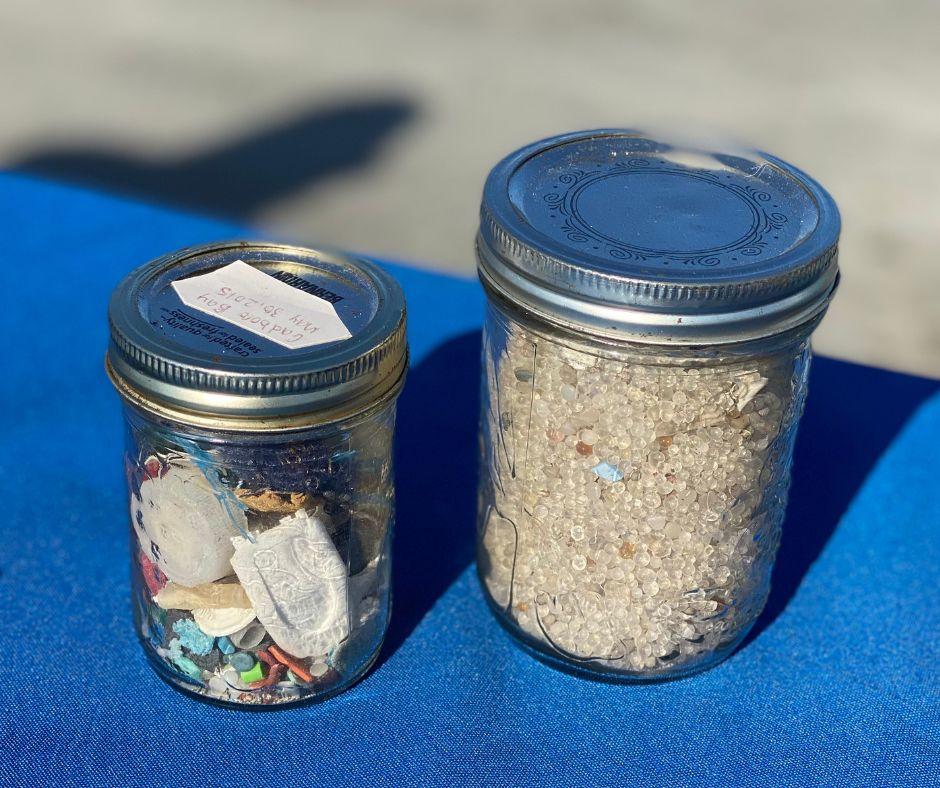 Two jars holding pieces of plastic and trash.
