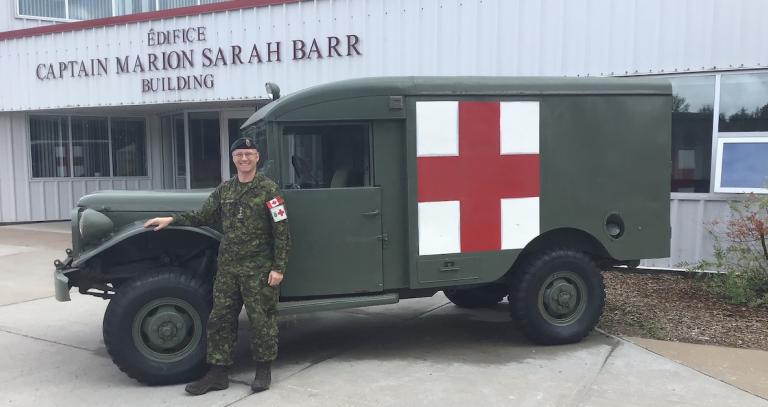 Alum Captain Mike Gauthier standing by a military medical vehicle.