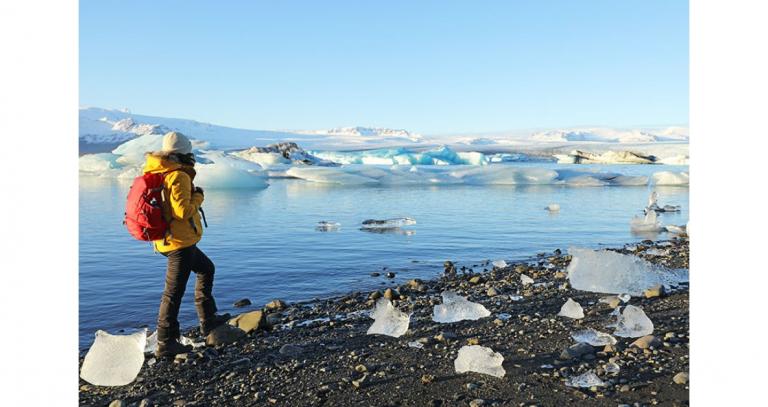 Hiker-walking-next-to-ocean-and-melting-icebergs