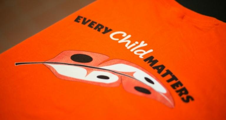 An orange t-shirt with "Every Chid Matters" and a feather. 