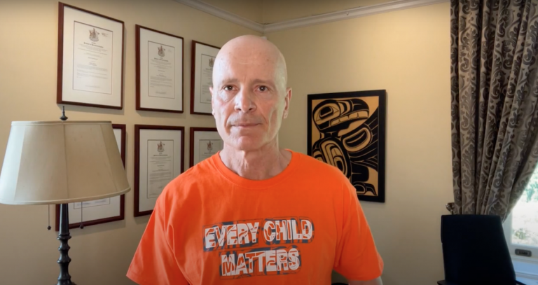 President Philip Steenkamp wearing an orange shirt that reads "every child matters" in his office.