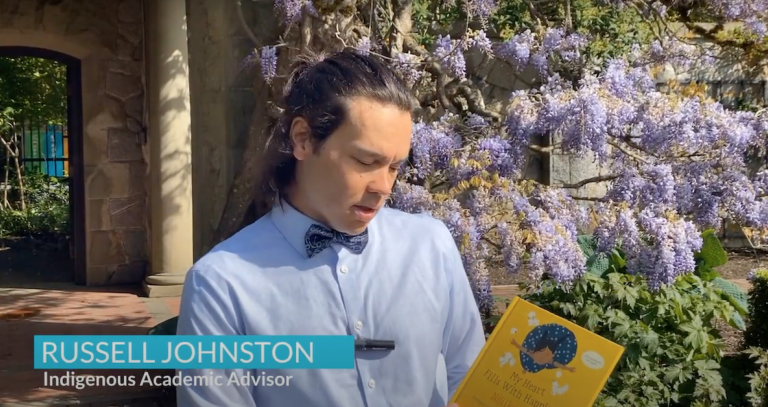 Russell Johnston in a bow tie reading "My Heart Fills with Happiness" in an Italian garden filled with Wisteria.