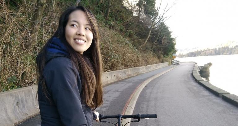 Vivian Giang standing next to bike on road
