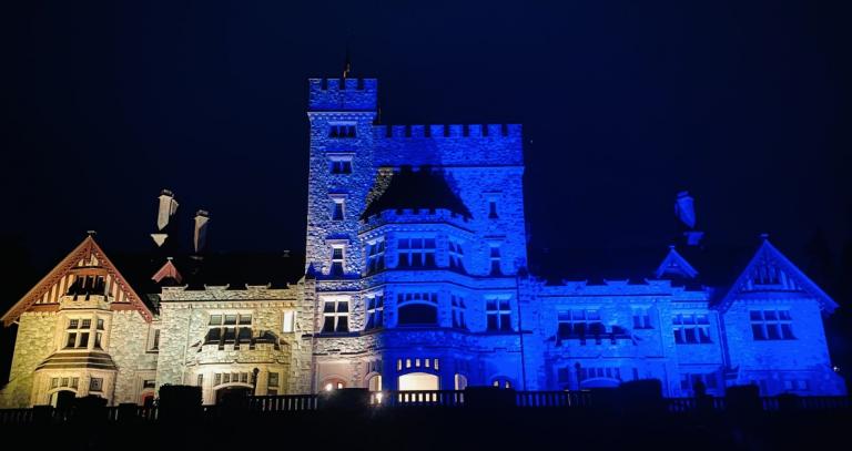Hatley Castle lit up at night with the yellow and blue colours of the Ukrainian flag.
