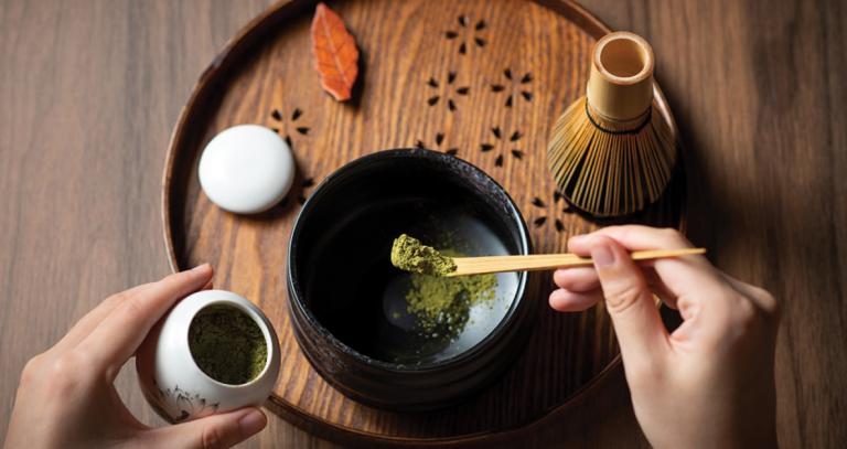 A person handling matcha powder on a wooden table 