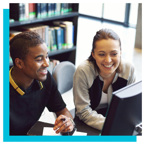 Two students working together on a computer in a library