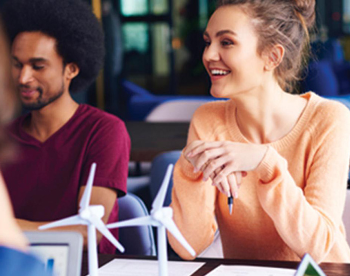 An RRU student sits at the table with their peers, smiling back at them in a lecture setting.