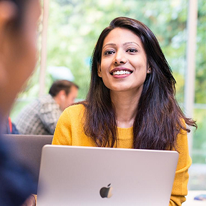 Student smiling over laptop with another student