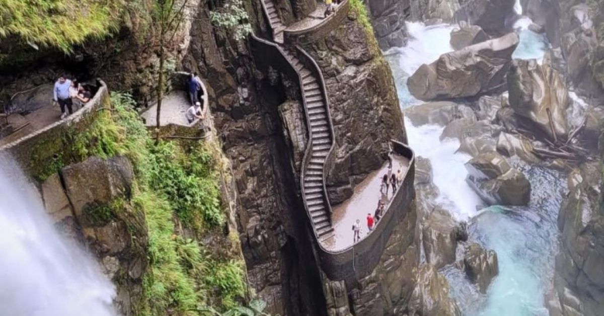 A stone staircase along the side of a cliff above a rushing waterfall and river.