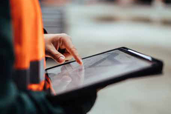 A security staff member point to a tablet they are holding in their hands