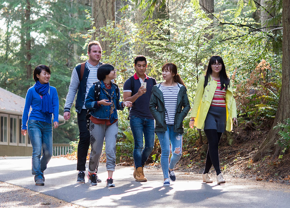 A group of RRU students walks together along a forested path. 