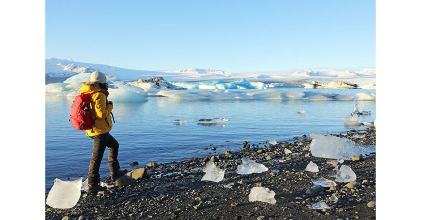 Hiker-walking-next-to-ocean-and-melting-icebergs