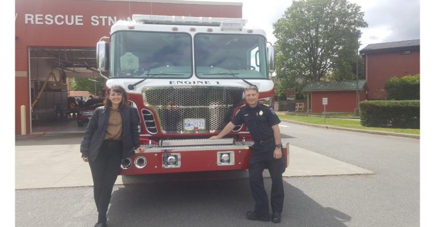 Student Jaya Bremer with a firefighter in front of a red fire truck