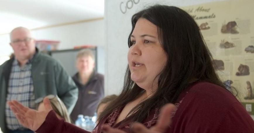 RRU alumni Charla Huber speaking in front of a display indoors