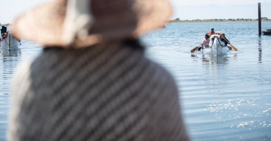 An Indigenous person waits onshore at Esquimalt Lagoon as a canoe arrives to ask for permission to land in a canoe protocol.