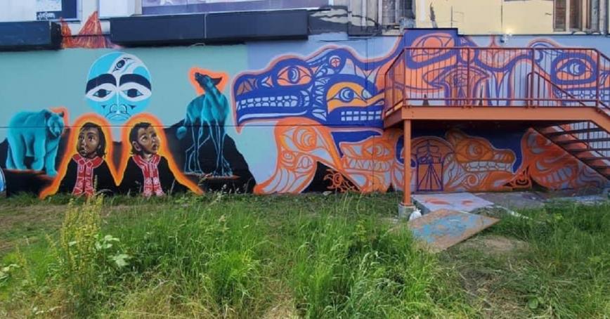 Mural of two Indigenous children flanked by a bear and a wolf with a blue moon rising above them.