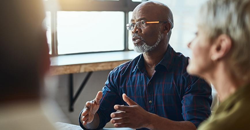 man sitting at a table talking with a group