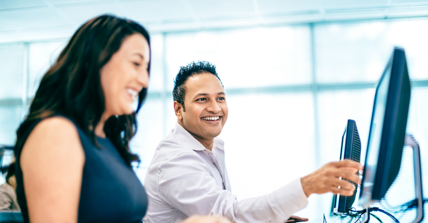 man and women smiling at computer