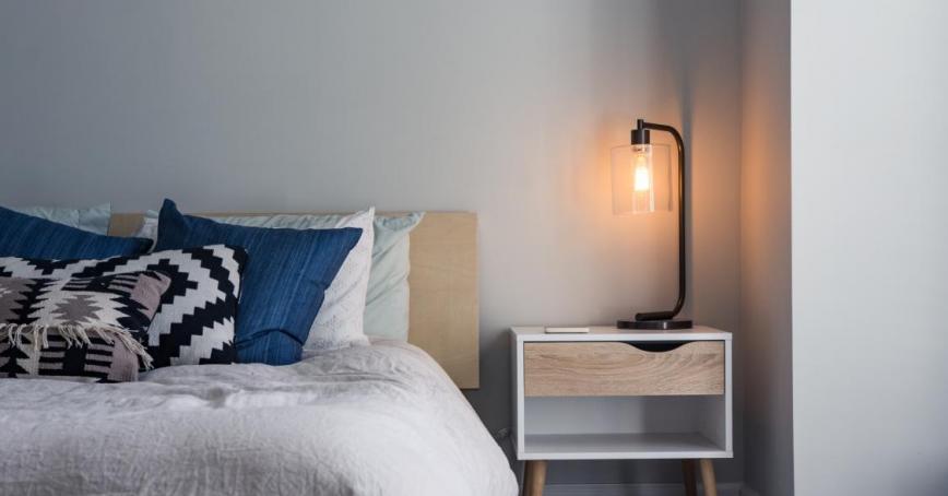 A photo of a bed with pillows and a lamp on a bedside table