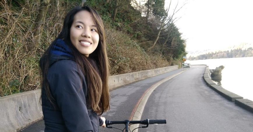 Vivian Giang standing next to bike on road