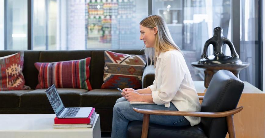 A woman sitting in a chair and looking at a laptop