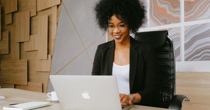 A photo of someone smiling and looking at a laptop