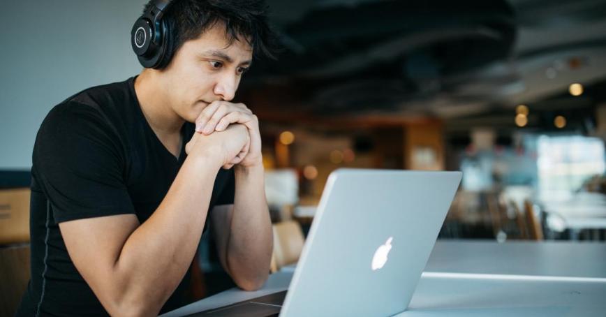 A photo of someone staring at a computer screen while wearing headphones