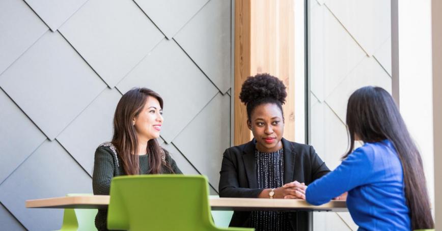 3 students sitting at a table talking