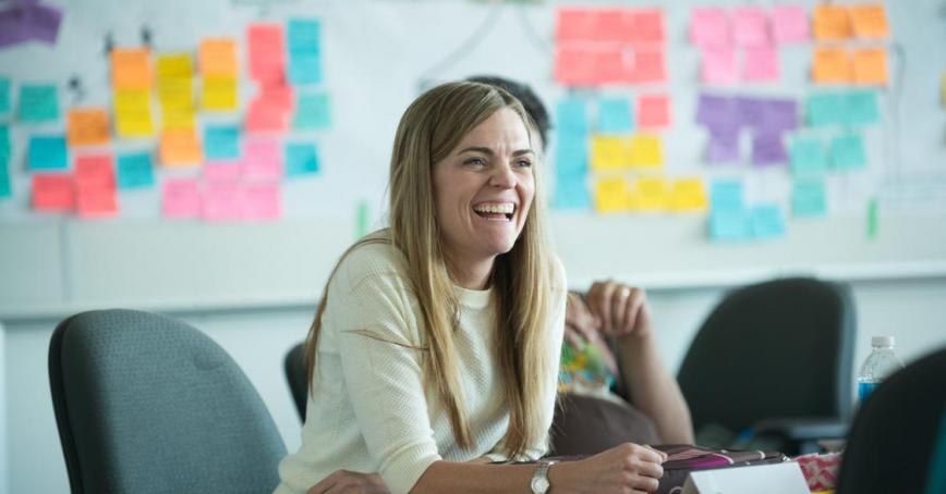 MBA student smiling at a desk with post-it notes in the background.