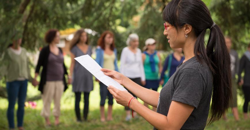 Student reading a paper in front of the outdoor classroom 