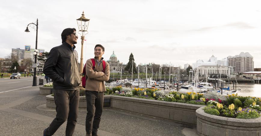 two people walking along the inner harbour walkway in Victoria, BC