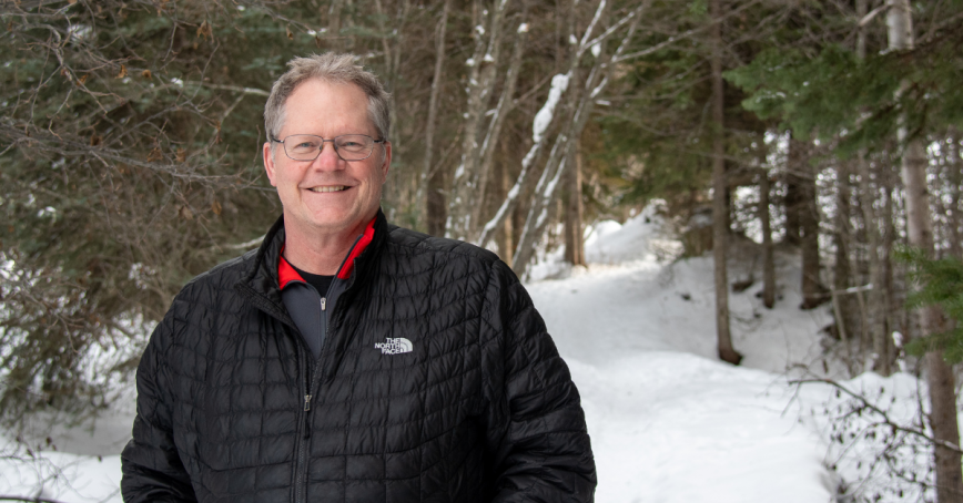 Dr. Graham Dodd head shot standing outside in the winter with the snowy forest behind