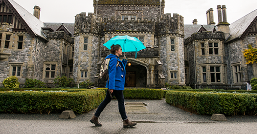 A student wearing blue walking in front of Hatley Castle