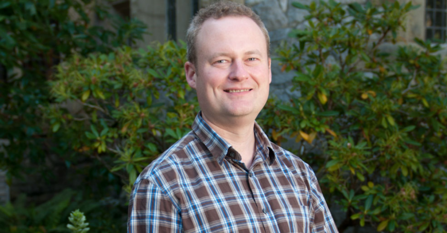 Head shot of Chris Ling with a bush in the background