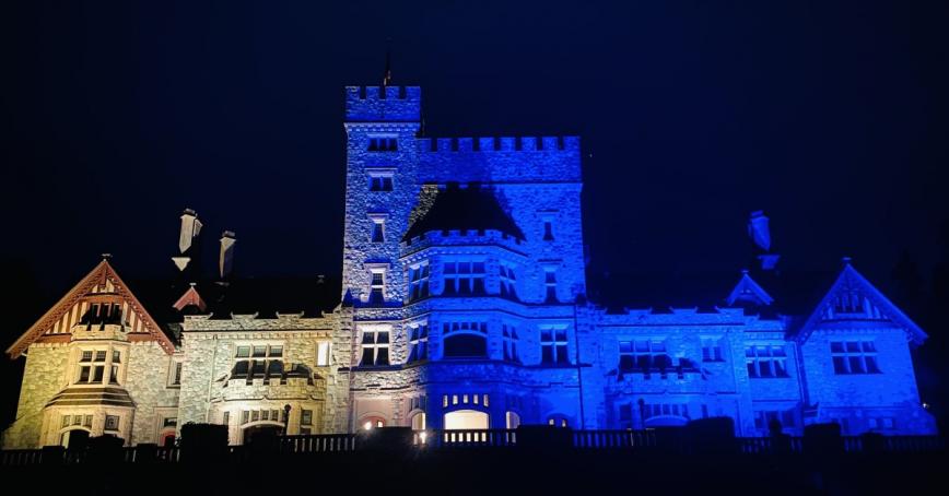 Hatley Castle lit up at night with the yellow and blue colours of the Ukrainian flag.
