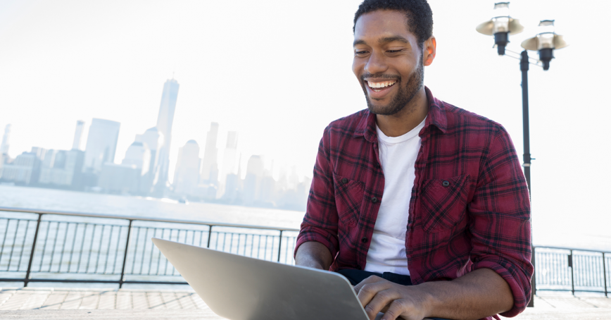 Student looking at its laptop, smiling.
