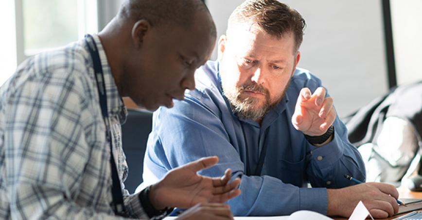 two people sitting at a table working together