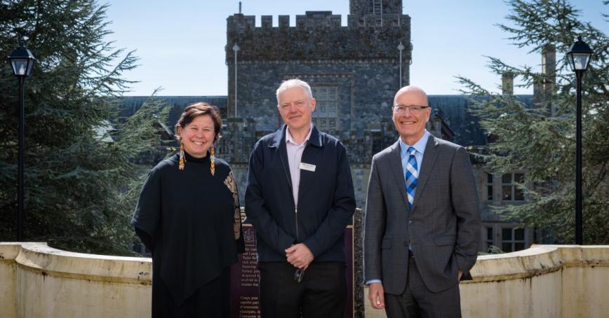 Deborah Saucier, President of Vancouver Island University, with Craig Davis, President and Head of College for Pearson and Philip Steenkamp, President and Vice-Chancellor of Royal Roads, stand together at the top of the Neptune Stairs. Hatley Castle is visible in the background.