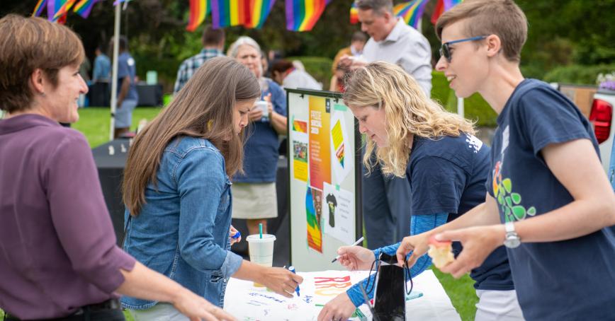 Four people at a Pride info table