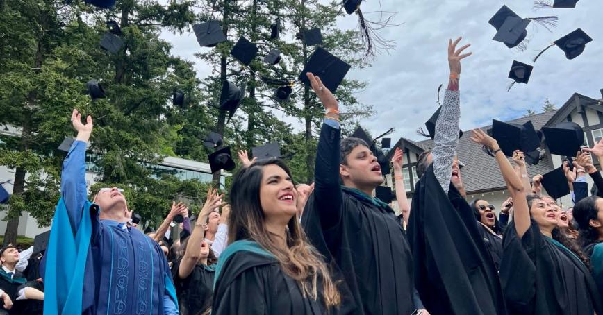 President Steenkamp and grads celebrate by throwing mortarboards into the air at Spring Convocation 2022.