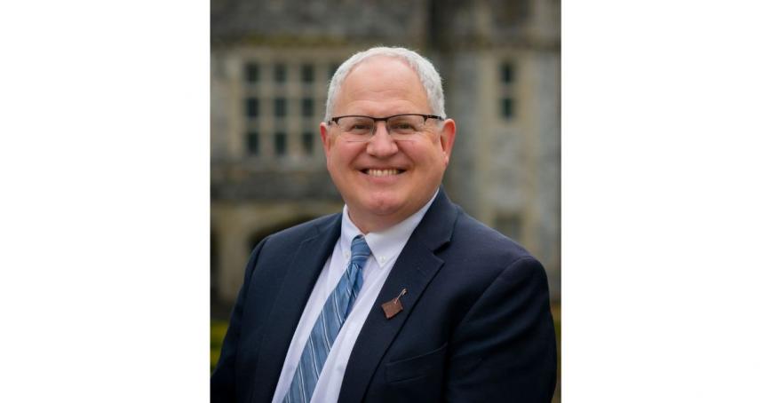 Kevin Brewster smiles at the camera, Hatley Castle is in the background.